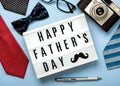 Happy Father`s Day.Lightbox with the word Happy Father`s Day next to ties,bow tie,retro photo camera,glasses and pen Royalty Free Stock Photo