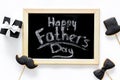 Happy Father`s day cards. Black tie, mustache and hat cookies and gift. White desk background top view Royalty Free Stock Photo