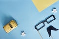 Happy Fathers Day top view. Decorative black paper mustache, glasses and yellow toy car on a blue background with place for text