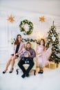 Happy father sits in an armchair and his big family stand next to a Christmas tree Royalty Free Stock Photo