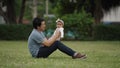 happy father sitting and kissing his infand baby on a green grass filed in park