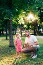 Happy father with a small daughter at sunset blowing soap bubbles in a summer park outdoors Royalty Free Stock Photo