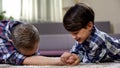 Happy father and son armwrestling on floor, little boy winning, free time