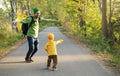 Happy father and son enjoying good weather during fall season. Cheerful dad and child dancing on the empty road in autumn park.