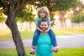 Happy father and son enjoying summer time on vacation in a sunny park. Dad carrying on shoulders happy little boy. Royalty Free Stock Photo