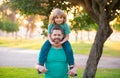 Happy father and son enjoying summer time on vacation in a sunny park. Dad carrying on shoulders happy little boy. Royalty Free Stock Photo