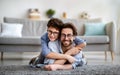 Happy father and son having fun at home. Dad lying on carpet carrying boy on back and smiling together to camera Royalty Free Stock Photo