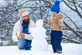 Happy father and son making snowman in the snow. Handmade funny snow man. Winter background with snowflakes and snowman. Royalty Free Stock Photo