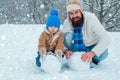 Happy father and son making snowman in the snow. Handmade funny snow man. Best winter game for happy family. Christmas Royalty Free Stock Photo