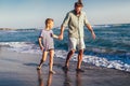 Happy father and son, man & boy child, running and having fun in the sand and waves on the beach Royalty Free Stock Photo