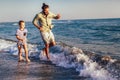 Happy father and son, man & boy child, running and having fun in the sand and waves on the beach Royalty Free Stock Photo