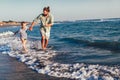 Happy father and son, man & boy child, running and having fun in the sand and waves on the beach Royalty Free Stock Photo