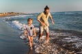 Father and son, man & boy child, running and having fun in the sand and waves of a sunny beach Royalty Free Stock Photo