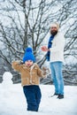 Happy father and son play on winter Christmas time. Father and son play with snowball on winter white background.