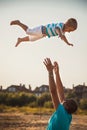 Happy father and son playing together at beach. Father throwing his son in the air