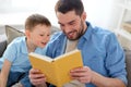 Happy father and son reading book sofa at home Royalty Free Stock Photo