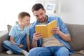 Happy father and son reading book sofa at home Royalty Free Stock Photo