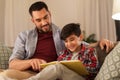 Happy father and son reading book sofa at home Royalty Free Stock Photo