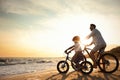 Father with son riding bicycles on sandy beach near sea at sunset Royalty Free Stock Photo