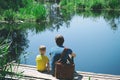 Happy father and son sitting on wooden pier near lake on summy summer day. Dad and child boy spend time together on nature Royalty Free Stock Photo