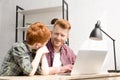 happy father and son smiling each other while using laptop together Royalty Free Stock Photo