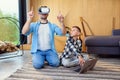 Happy father and son in virtual reality headsets playing with gamepads at home. Augmented reality concept. Royalty Free Stock Photo