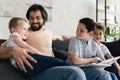 happy father and sons resting on sofa while reading book together Royalty Free Stock Photo