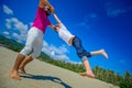 Happy father is spinning in circle his adorable boy. Sunny tropical beach, palm trees behind Royalty Free Stock Photo