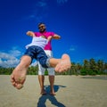 Happy father is spinning in circle his adorable boy. Sunny tropical beach, palm trees behind Royalty Free Stock Photo