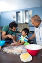 Happy father sprinkling flour on son hand while preparing food with grandfather Royalty Free Stock Photo