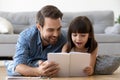 Happy father and surprised kid girl reading book together