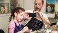 Happy father taking photos of his cute little daughter while she is drawing Royalty Free Stock Photo