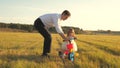 Happy father teaches little daughter to ride a bike. Dad plays with small child on lawn. kid learns to ride bicycle Royalty Free Stock Photo