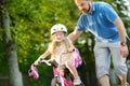 Happy father teaching his little daughter to ride a bicycle. Child learning to ride a bike. Royalty Free Stock Photo