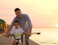 Happy father teaching his son to ride bicycle near river Royalty Free Stock Photo