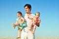 Happy father with two babies outdoors. Dad playing with daughters in sunny summer day. Father holding child. Portrait on blue sky. Royalty Free Stock Photo