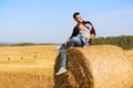Happy father and two year old girl sitting on hay bales in field
