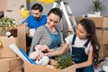 Happy father and wife and daughter sort things out from cardboard boxes in house they moved.