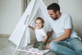 Happy father young man and baby girl little daughter having fun playing in wigwam in children room at home Royalty Free Stock Photo