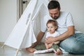 Happy father young man and baby girl little daughter having fun playing in wigwam in children room at home Royalty Free Stock Photo