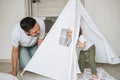 Happy father young man and baby girl little daughter having fun playing in wigwam in children room at home Royalty Free Stock Photo