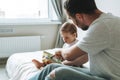 Happy father young man and baby girl little daughter having fun reading a book in children room at home Royalty Free Stock Photo