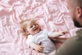 Happy father young man and baby girl little daughter having fun on bed in room at home Royalty Free Stock Photo