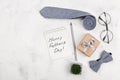 Happy Fathers Day background with notebook, gift, glasses, necktie and bowtie on white table top view in flat lay style.