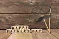 Happy Fathers Day blocks with mustache and glasses against wood Royalty Free Stock Photo