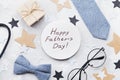 Happy Fathers Day card decorated bowtie, necktie, eyeglasses, gift box and stars on stone table top view in flat lay style. Royalty Free Stock Photo