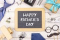 Happy Fathers Day chalkboard with frame of gifts, ties and decor on white wood Royalty Free Stock Photo