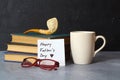 Happy Fathers day concept with coffee cup, pipe, glasses and books over wooden background