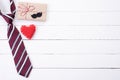 Happy fathers day concept. Top view of blue tie, beautiful gift box, red heart with man mustache on white wooden table background