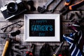 Happy fathers day concept. Top view of white picture frame with border of tools and ties, retro film camera on dark wooden table Royalty Free Stock Photo